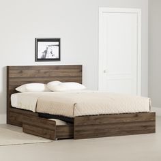 a bed with two drawers underneath it in a white room next to a door and rug