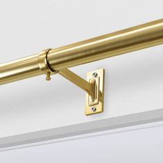 a close up of a gold curtain rod on a white wall with a diamond in the center