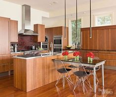 a kitchen with wooden floors and stainless steel appliances, including an island table surrounded by four chairs