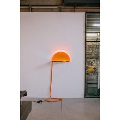 an orange lamp sitting on top of a white wall next to a black and gray object