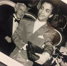 two men in tuxedos sitting next to each other on a bus with people behind them