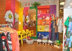 the children's clothing store is brightly colored and has wooden floors, colorful walls, and shelves with clothes on them