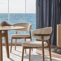 a dining room table with two chairs next to the ocean