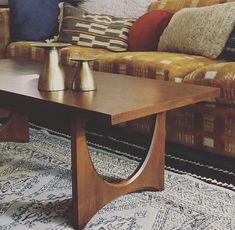 a wooden table sitting in front of a couch with pillows on top of the couch