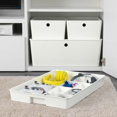 a white storage box filled with items on top of a carpet