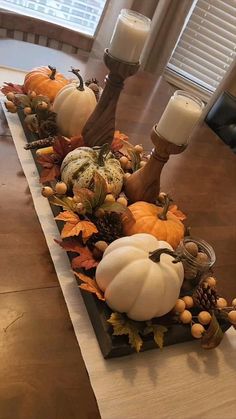 a long table with candles and pumpkins on it