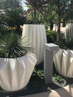 several large white planters in a garden