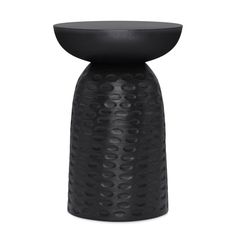 a black vase with holes on it and a round base in the middle, sitting on a white surface