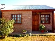 a small brick house with potted plants in the front and side yard area next to it