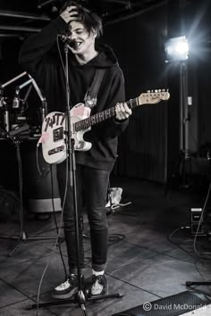 a young man standing in front of a microphone and guitar