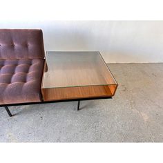 a chair and table sitting next to each other on concrete floor with white wall in background