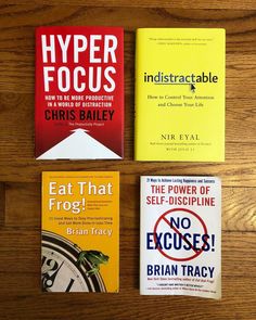 three books sitting on top of a wooden table next to each other and one has a clock