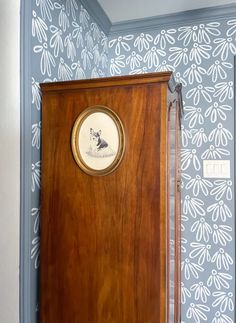 a wooden door with a clock on the front and side of it in a blue wallpapered room