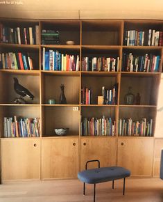 a living room with bookshelves and a bench in front of the bookcase