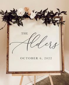 a sign that says the elders on it with flowers and greenery around it in front of a white wall