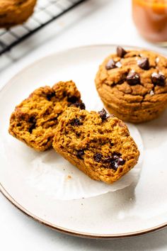 three chocolate chip muffins on a plate next to a glass of orange juice