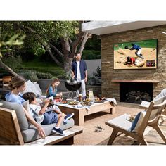 a group of people sitting around a table with food and drinks in front of a flat screen tv