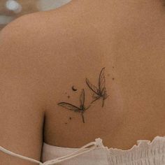 the back of a woman's shoulder with a small dragonfly tattoo on it