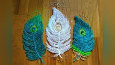 three different colored feathers sitting on top of a wooden floor