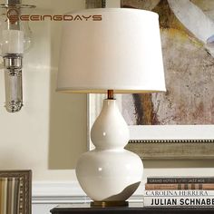 a white lamp sitting on top of a table next to a book shelf with books