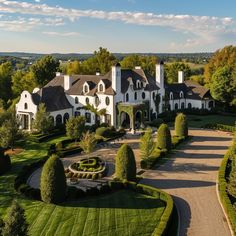 an aerial view of a large home surrounded by lush green trees and bushes, with a driveway leading to the front door