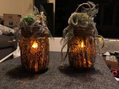 two jars with candles are sitting on a table