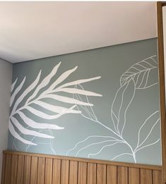 the wall is painted with white paint and has a palm leaf design on it, along with wood paneling