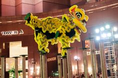 a yellow and black dragon statue in the middle of a building with people standing around it