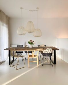 a dining room table with chairs and lights hanging from it's ceiling, in front of a window