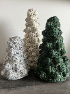 three crocheted trees sitting on top of a wooden table