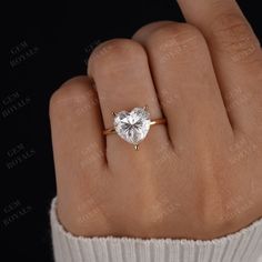 a woman's hand with a gold ring and a heart shaped diamond on it