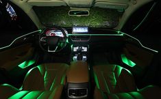 the interior of a car with green lights and leather seats, including an electronic display