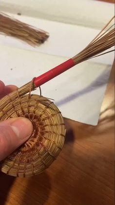 a person is holding a wicker basket with a red handled stick in their hand