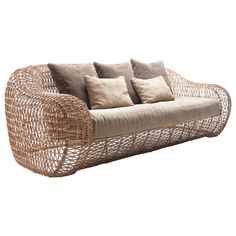 a wicker couch with four pillows on the back and one seat upholstered