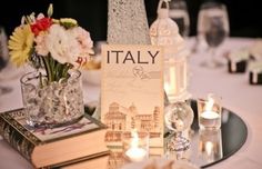 a table topped with books and vases filled with flowers on top of a white table cloth