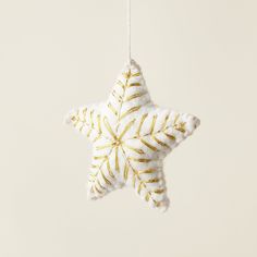 a white and gold star ornament hanging from a string