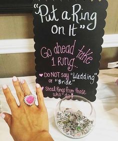 a woman's hand with pink and white nails next to a sign that says put a ring on it