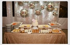 a table topped with lots of food and desserts next to disco ball wallpaper