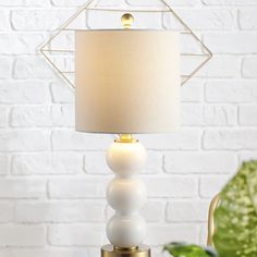 a white lamp sitting on top of a table next to a potted green plant