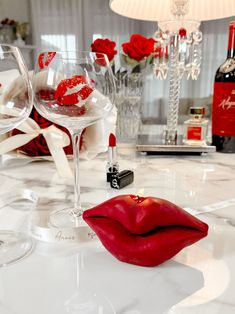 a table with wine glasses and red lips on it, next to a bottle of champagne