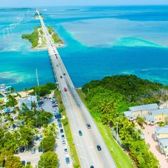 an aerial view of the ocean and road with cars driving on one side, surrounded by palm trees