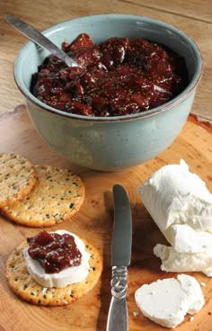 a bowl of jam and crackers on a wooden board