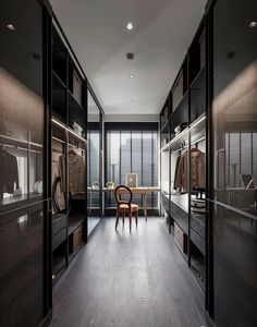 a walk in closet filled with lots of brown furniture and clothes hanging on glass doors