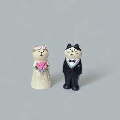 two small figurines of cats dressed up as bride and groom, one wearing a tuxedo