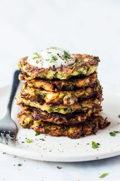 a stack of zucchini fritters on a plate with a fork