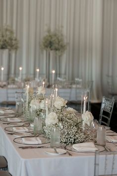 the table is set with white flowers and candles