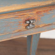 an old wooden table with metal knobs on the top and bottom drawer, painted blue