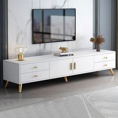 a white entertainment center with gold accents and a flat screen tv mounted on the wall