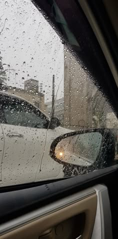 the rain is falling on the windshield of a car as it sits in front of a building