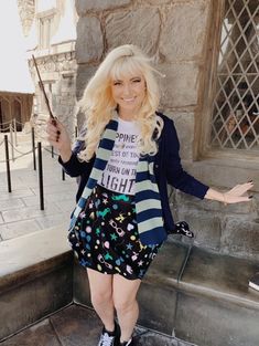 a woman with blonde hair is posing for a photo in front of a stone building